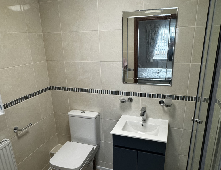 Tiled Bathroom With Sink and mirror